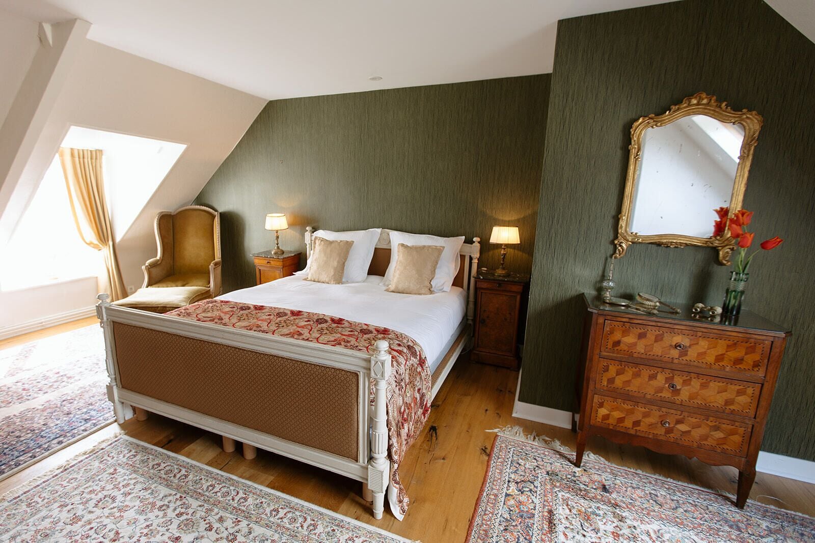 A bedroom with a bed, a dresser, a mirror, and a chair.