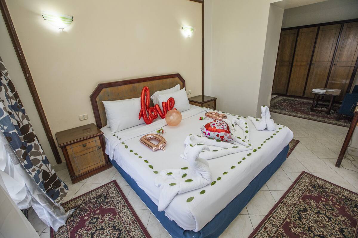 A hotel room with a bed, a nightstand, a wardrobe, and a bathroom with a shower curtain.