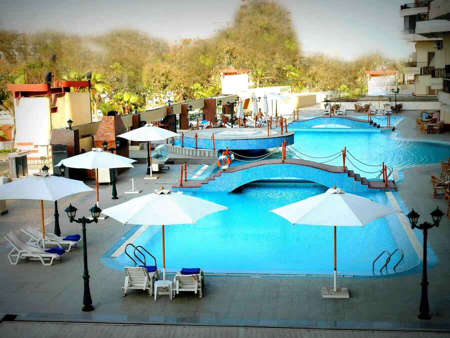 Een buitenzwembad, parasols bij het zwembad en ligstoelen