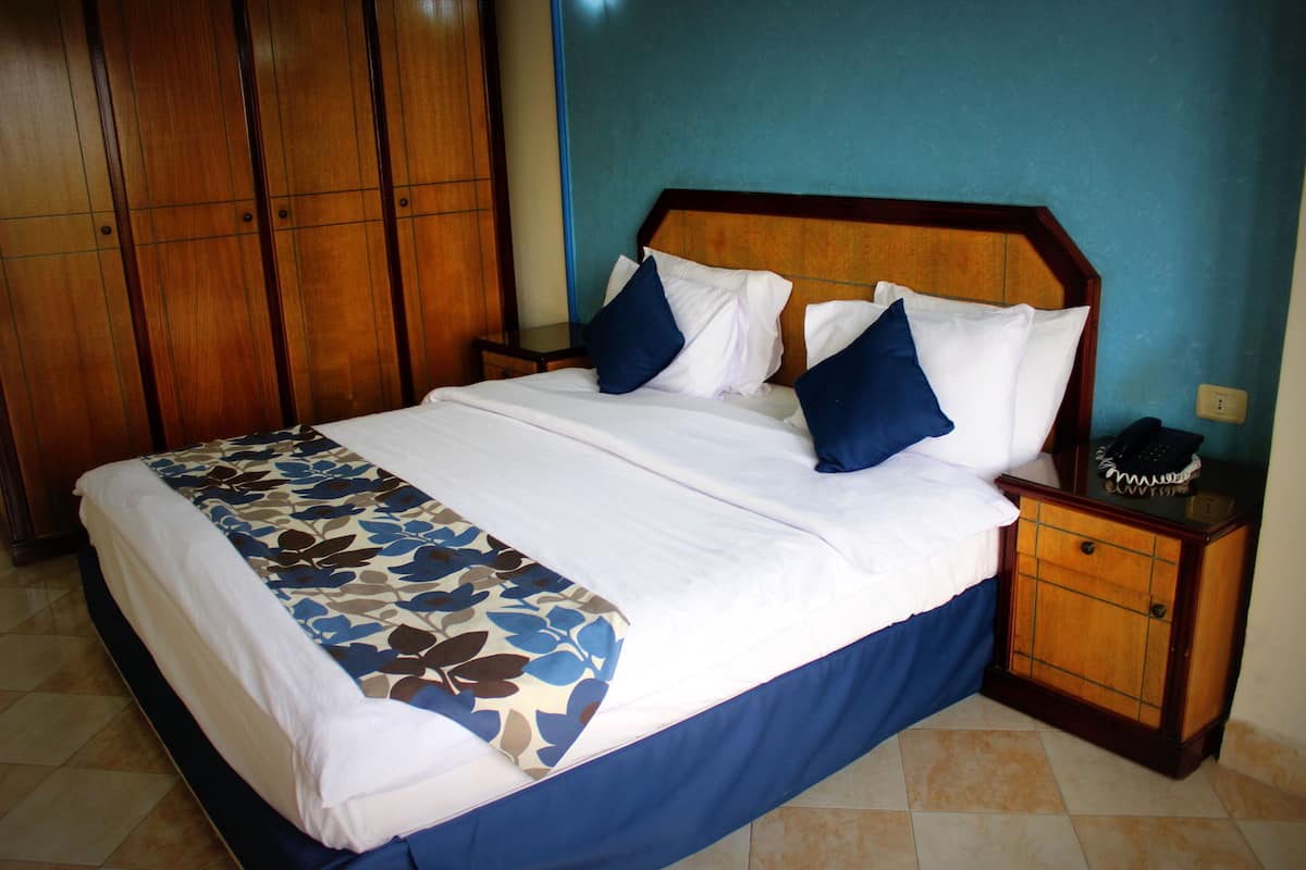 A bed with a floral bedspread, a wooden headboard, and a nightstand with a telephone.