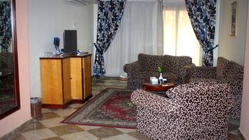 A living room with patterned sofas, a wooden cabinet, and a red rug.