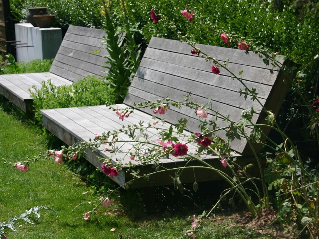 Eine hölzerne Bank mit rosa Blumen in einem Garten.