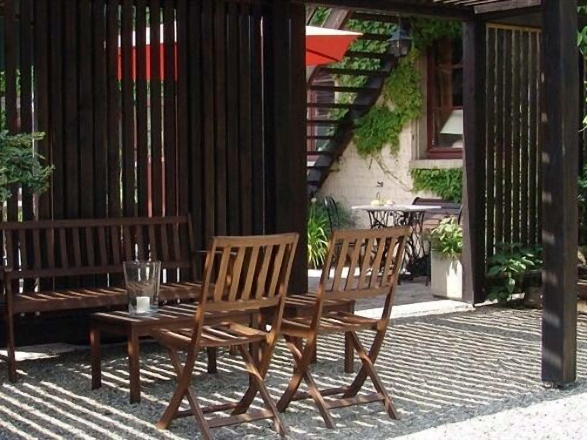 Een terras buiten met houten meubels en een stenen vloer.