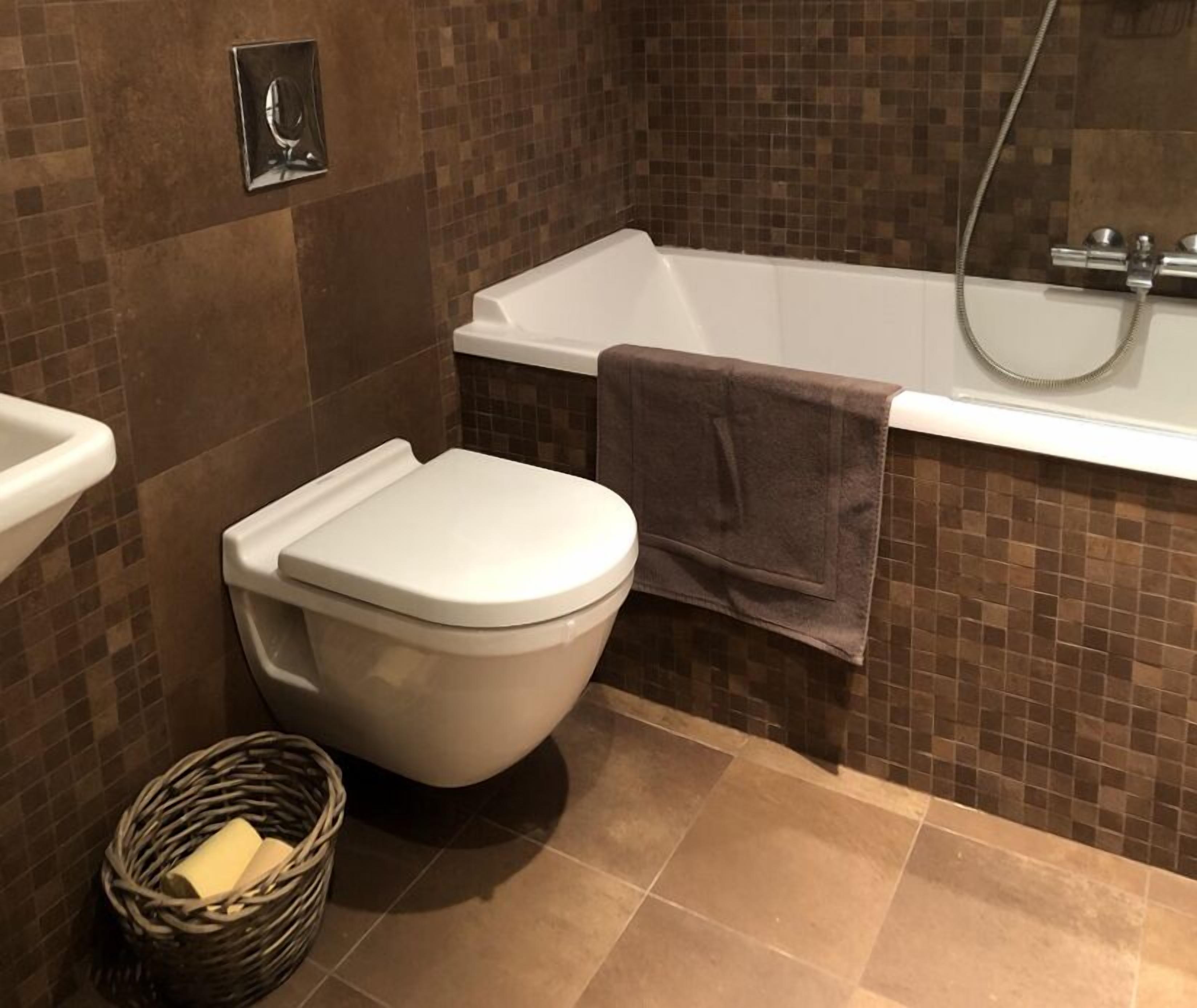 Une salle de bain avec des toilettes blanches, une baignoire et une douche.