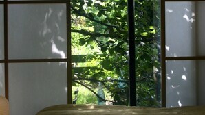 A room with a bed, a window with a view of greenery, and a bottle on the windowsill. - Lescalier (Brumath)
