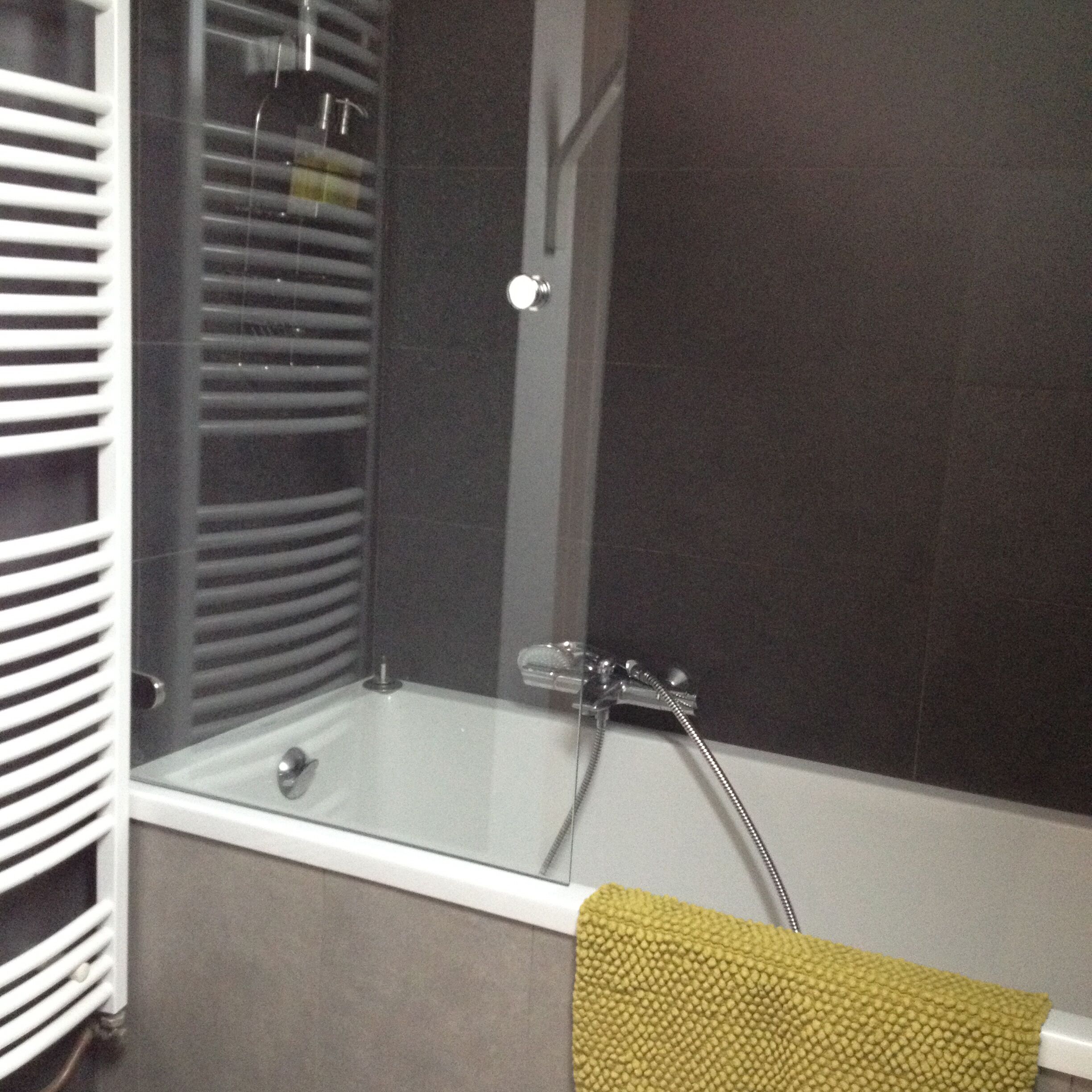Ein Badezimmer mit einer Duschkabine, einem Handtuchhalter und einer weißen Badewanne.