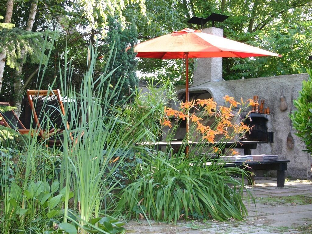 A patio area with a stone wall, a grill, and an umbrella.