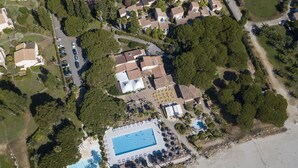 Vista aérea de un resort con una gran piscina, varias construcciones y follaje circundante.