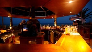 Zona de bar con vista al océano, amueblada con taburetes y barra.