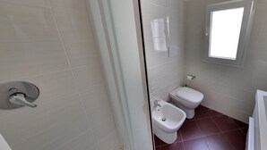 A bathroom with a toilet, bidet, and a small window. - B&B del Carmine (Noto)