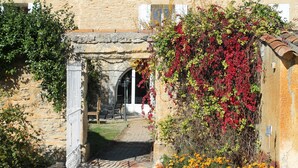 A stone building with a rustic entrance, a metal gate, and a pathway leading to an arched doorway. - La Mandarine (Piolenc)