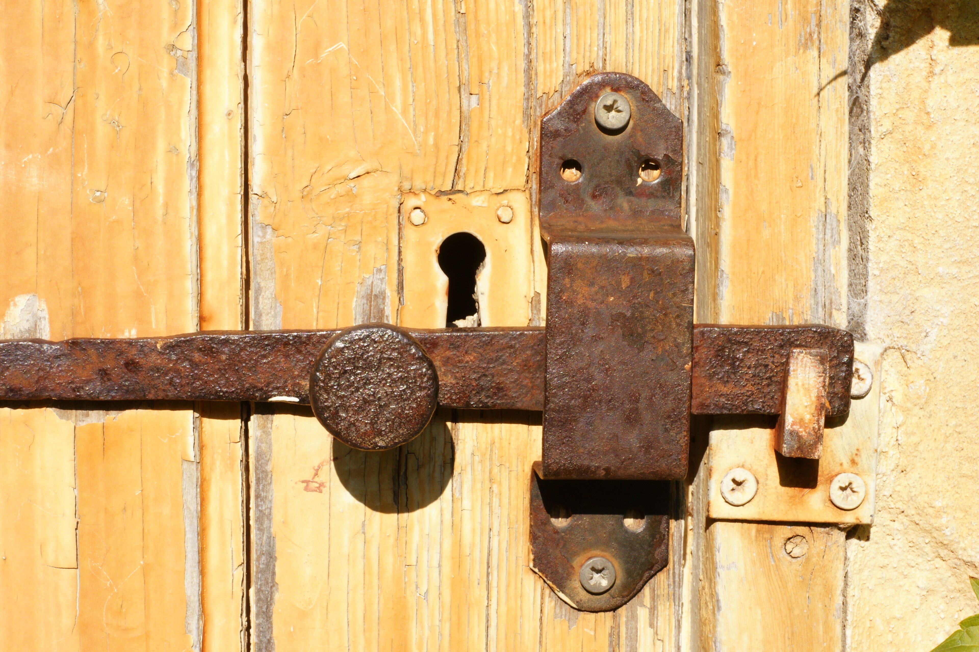A wooden door with a metal latch and a keyhole.