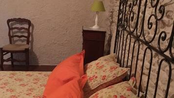 A bedroom with a bed, a chair, a nightstand, a lamp, and a painting on the wall.