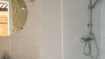 Un baño con un lavamanos blanco, un espejo y una ducha con cabezal de ducha de mano.