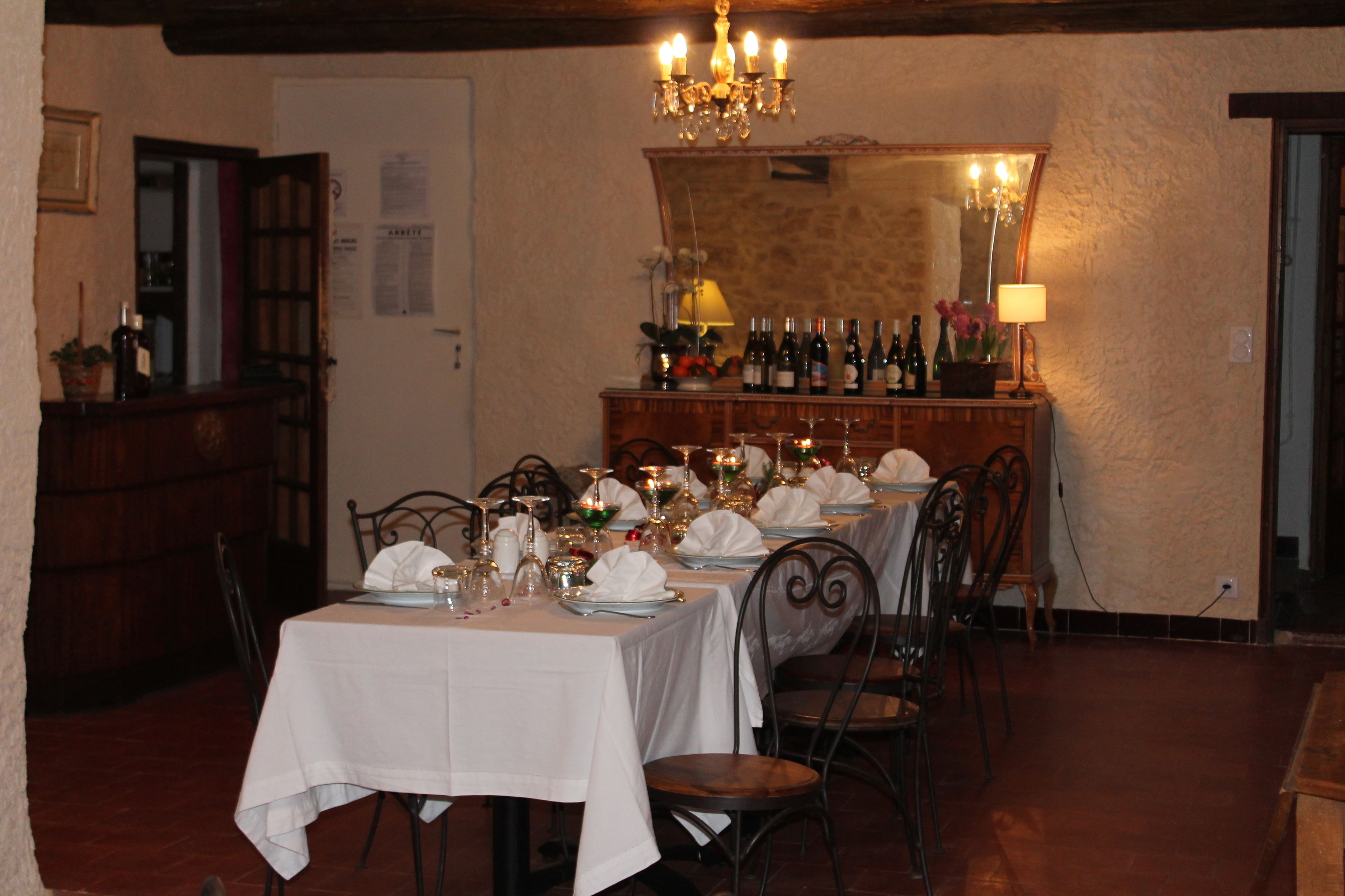 A dining area with tables set for a meal, a bar with bottles, and a chandelier.