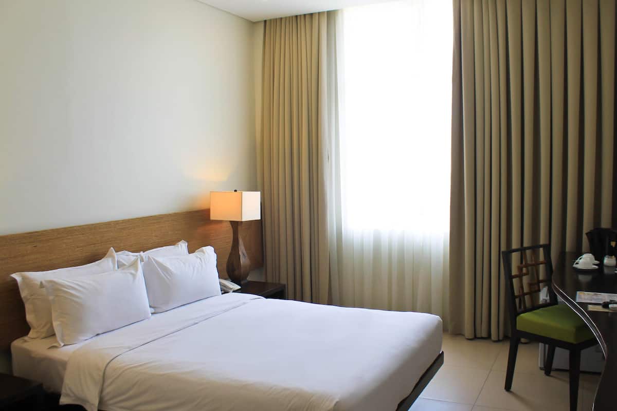 Une chambre d’hôtel avec un grand lit, une table de chevet avec une lampe, une chaise et un bureau.