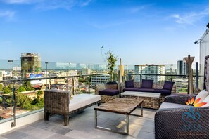 A rooftop terrace with outdoor furniture, a glass railing, and a city view. - Azia Suites and Residences (Cebu City)