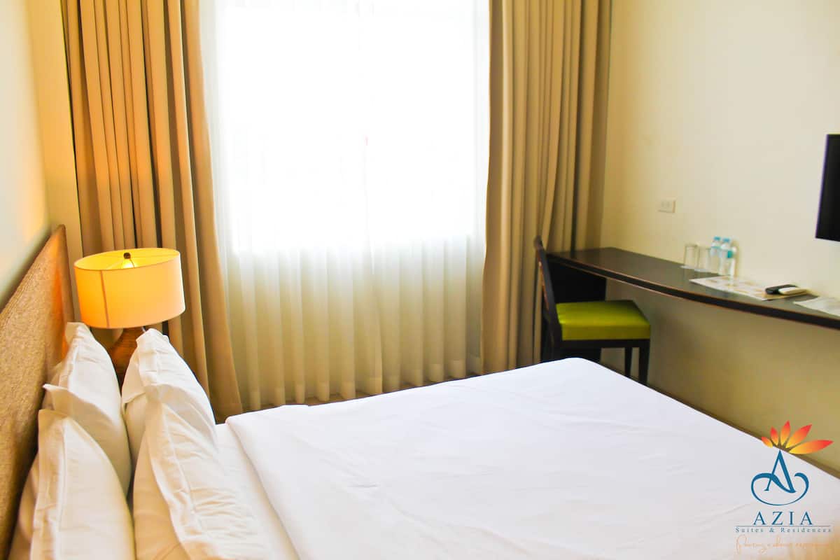 Une chambre d’hôtel avec un lit, un bureau, une lampe et une chaise.