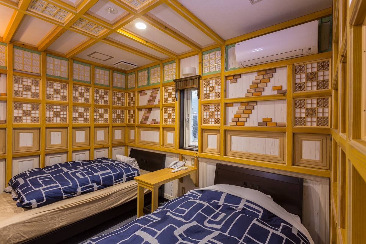A room with two beds, a desk, and a window.