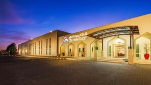 Un hôtel moderne doté d’une grande entrée, d’un espace abrité et d’une enseigne en arabe.
