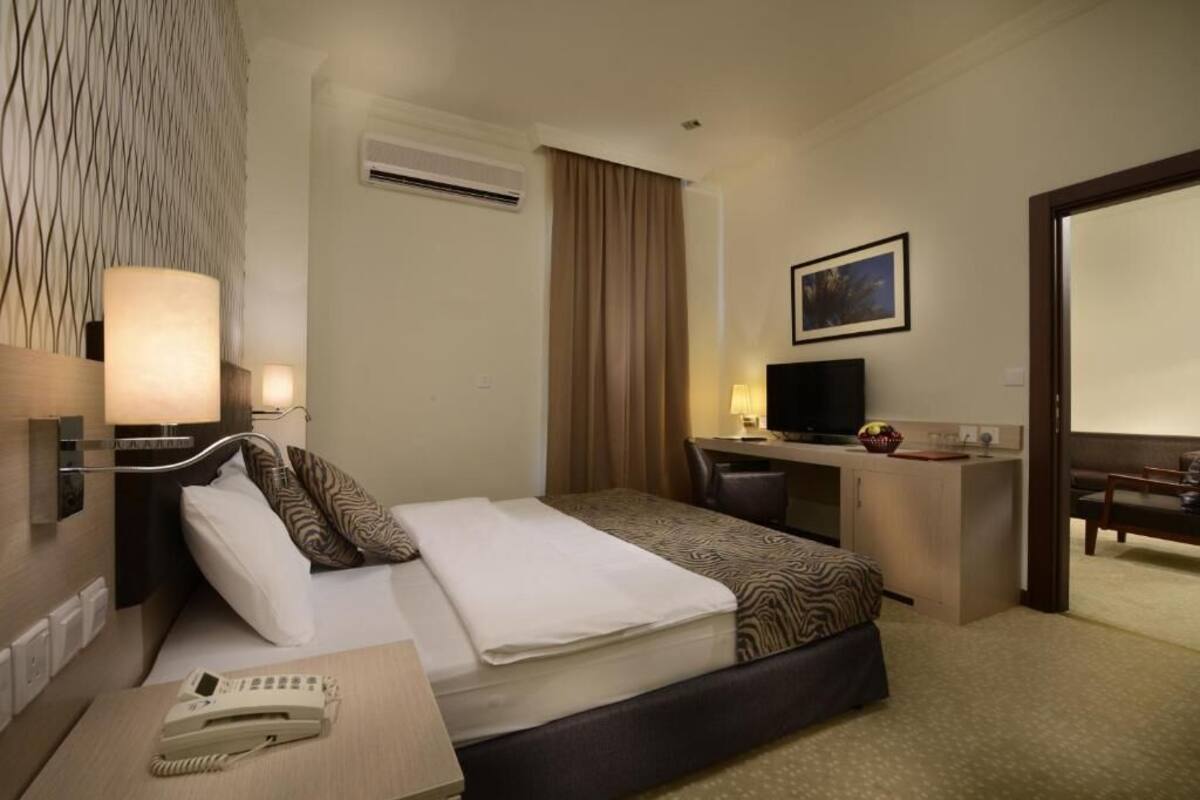 Una habitación de hotel con cama, escritorio, silla y televisión.