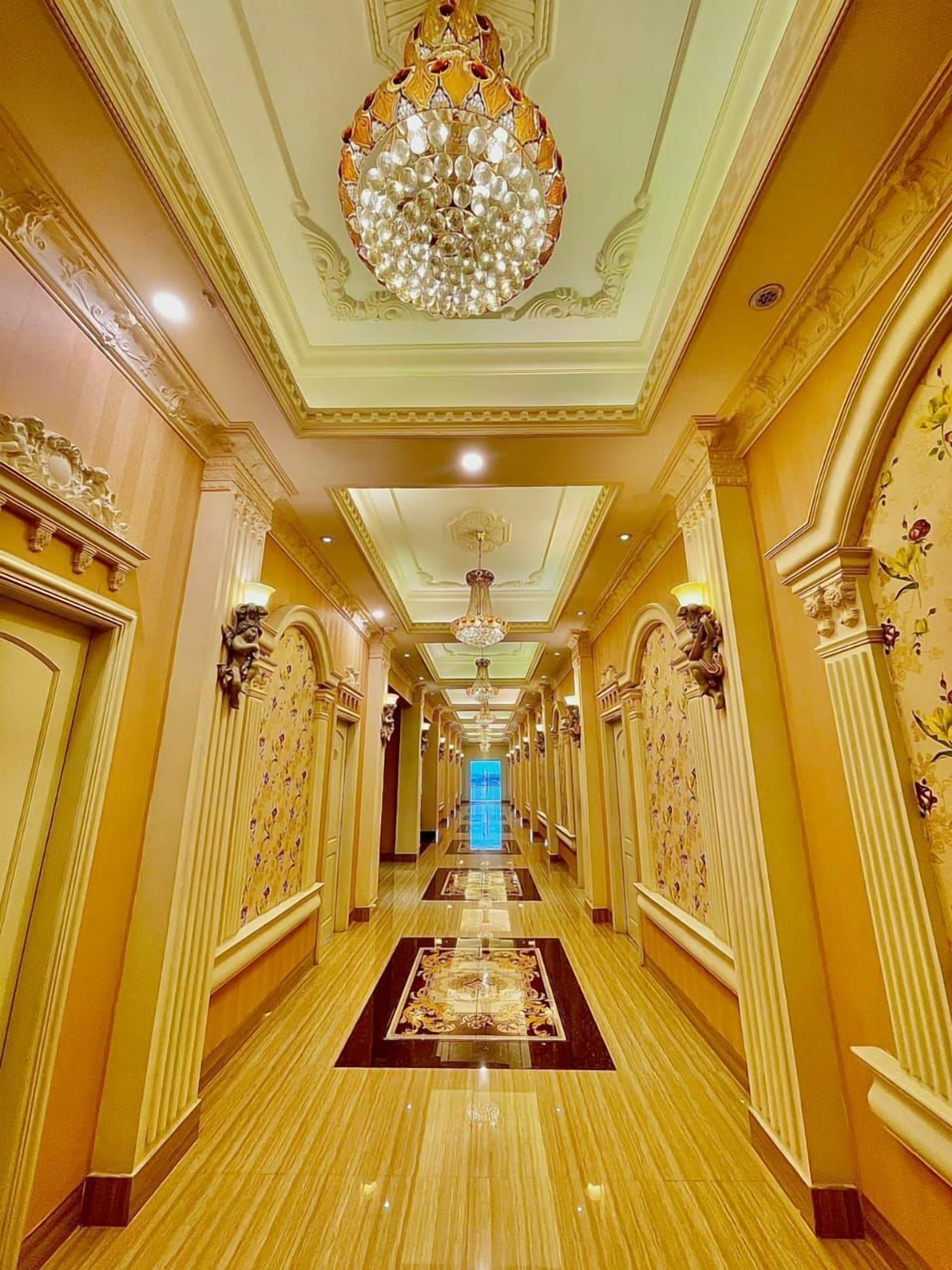 Un hall d’entrée luxueux, agrémenté de décorations raffinées, d’un lustre et d’un tapis à motifs.