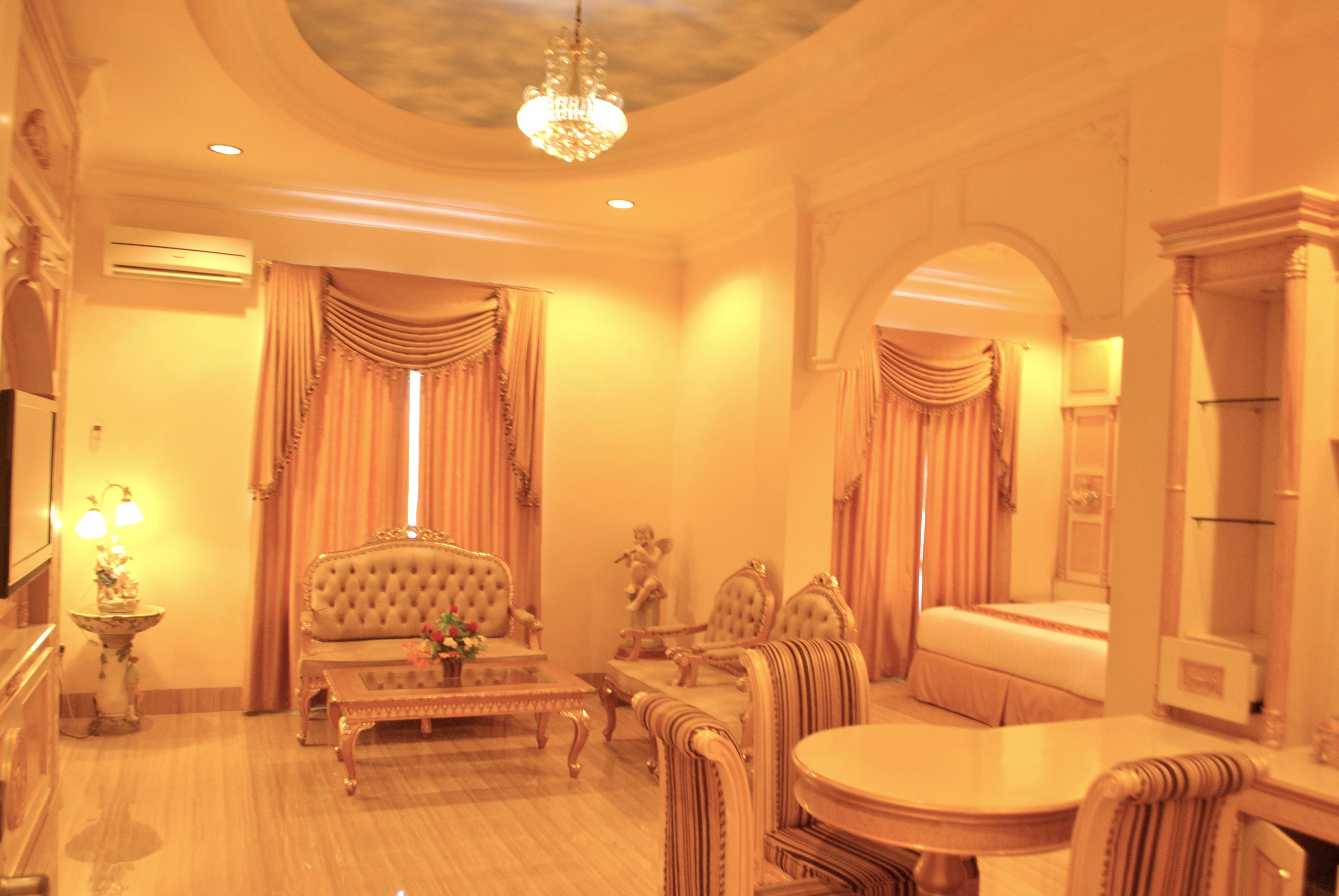 A luxurious room with a plush sofa, a round table, and a chandelier.