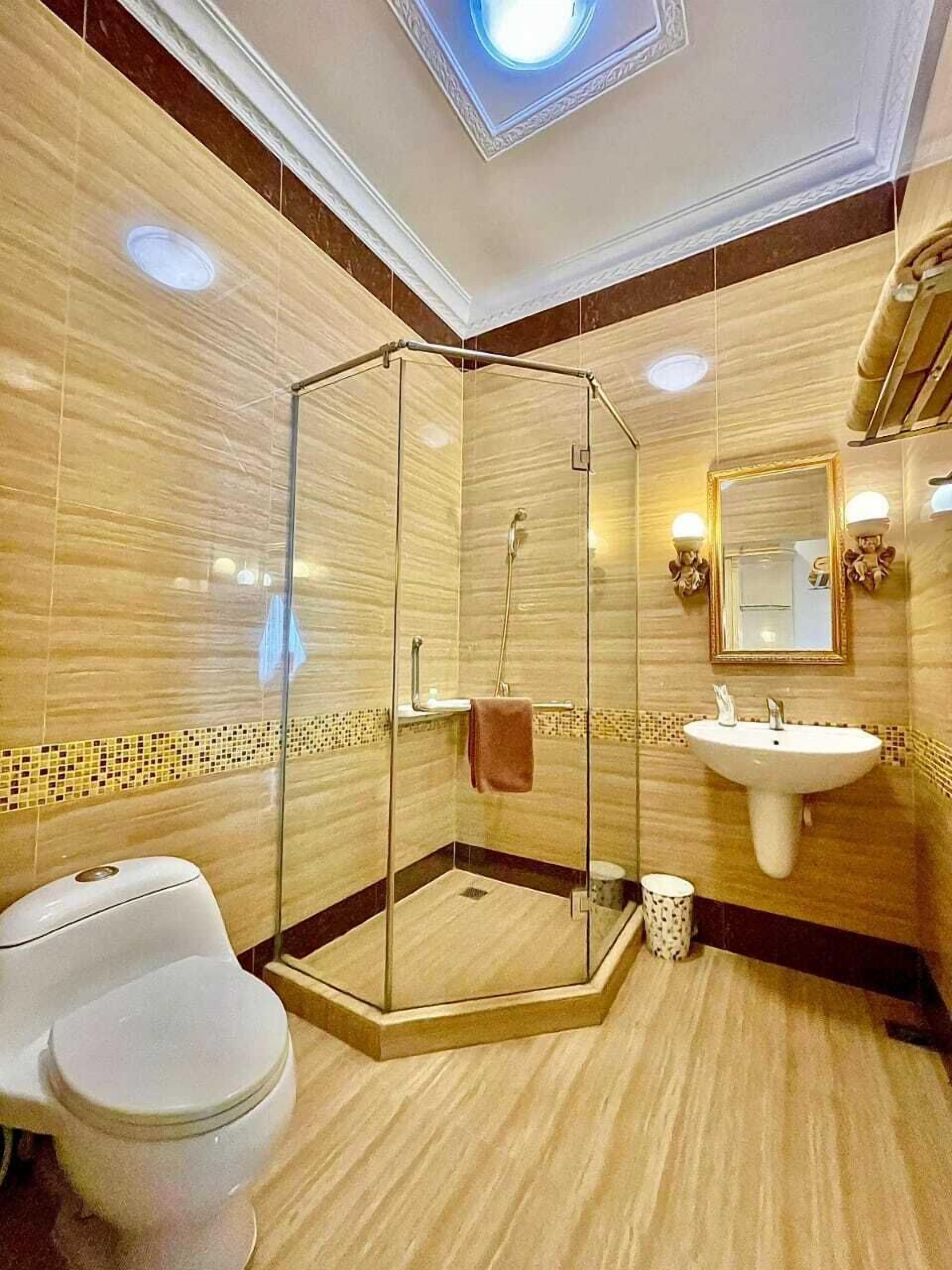 Ein modernes Badezimmer mit einer Duschkabine, einem weißen Waschbecken und einer Toilette.