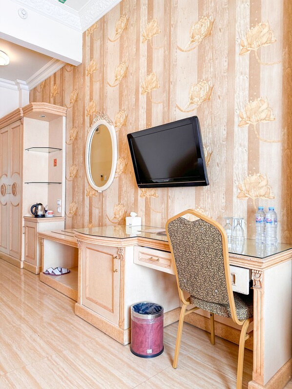 Habitación de hotel con tocador, televisión, espejo, escritorio y silla.