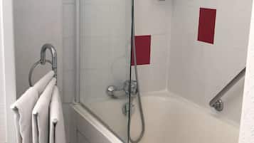 Et moderne badeværelse med et glasafskærmet brusebad, et badekar og en håndklædestang med flere håndklæder.