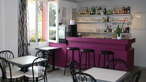 A bar area with a purple counter, multiple stools, and a variety of bottles and glasses on shelves. - Hotel Le Saint Remy (Saint-Remy)