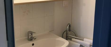 A bathroom with a sink, mirror, and towel rack.