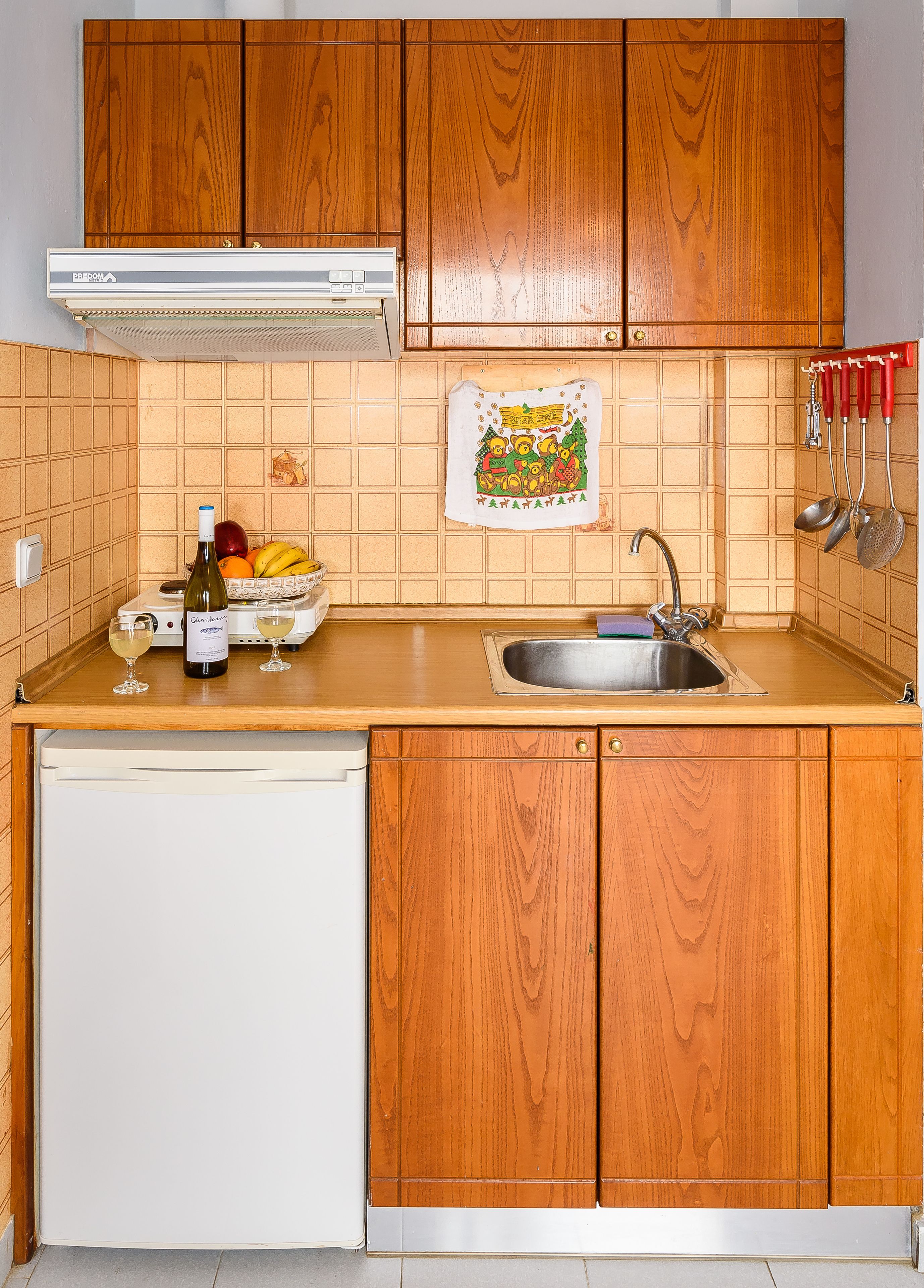 A kitchen with wooden cabinets, a white dishwasher, a sink, and a fruit bowl.