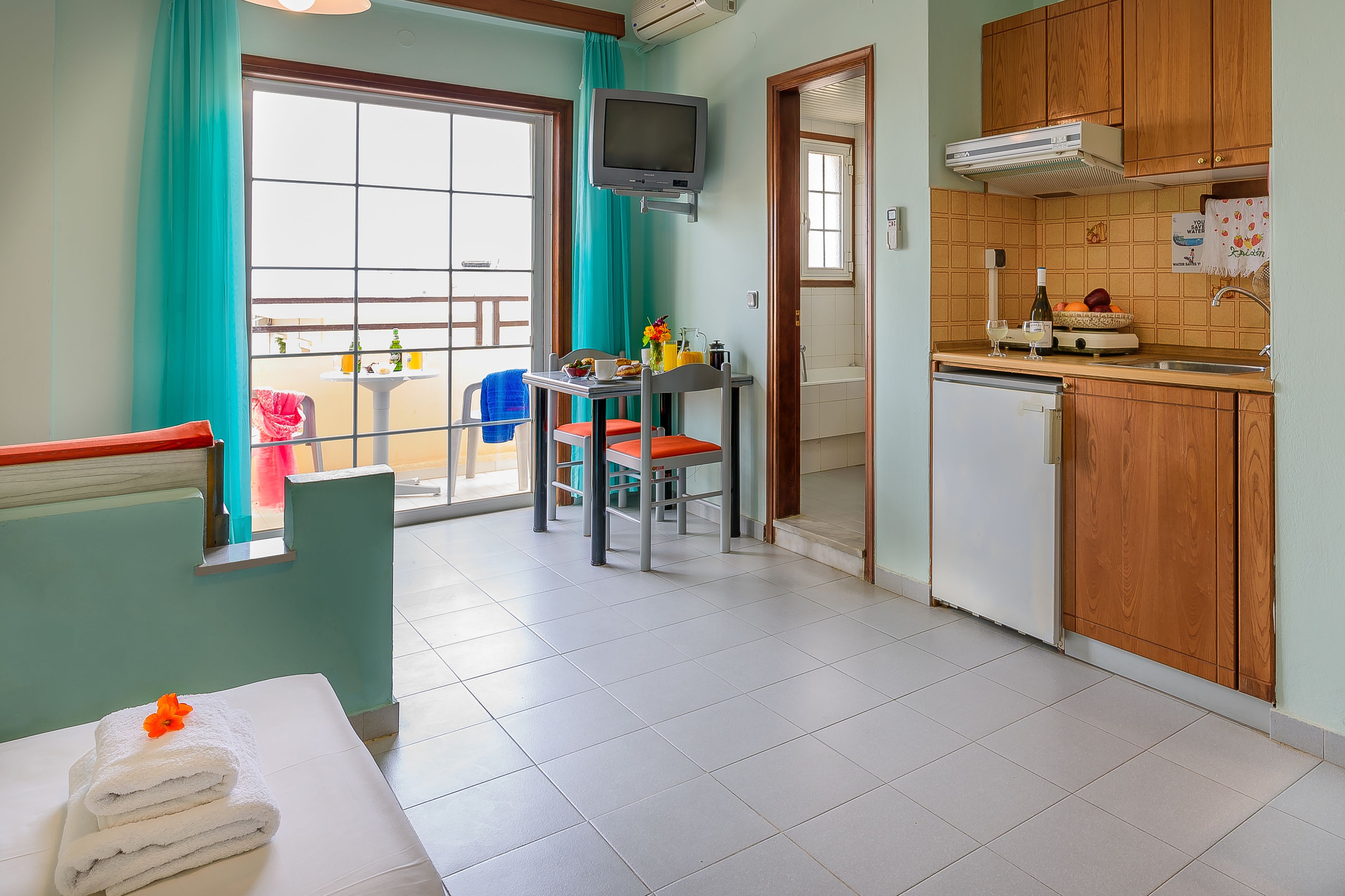 Cocina compacta con comedor, televisión y vistas al exterior.