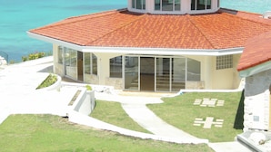 Un edificio de dos pisos con tejido rojo y amplias ventanas de vidrio, con vista al mar turquesa.