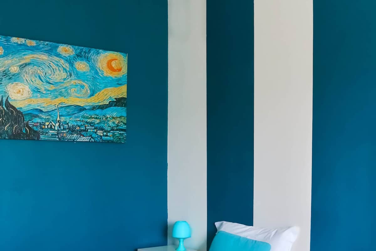 Een hotelkamer met twee bedden, een schilderij aan de muur en een nachtkastje met een lamp.