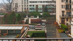 Een woongebouw met meerdere balkons, een dakbostuin en uitzicht op omliggende gebouwen.