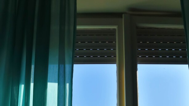 Een raam met uitzicht op een gebouw met rode en witte gevels en een helderblauwe lucht.