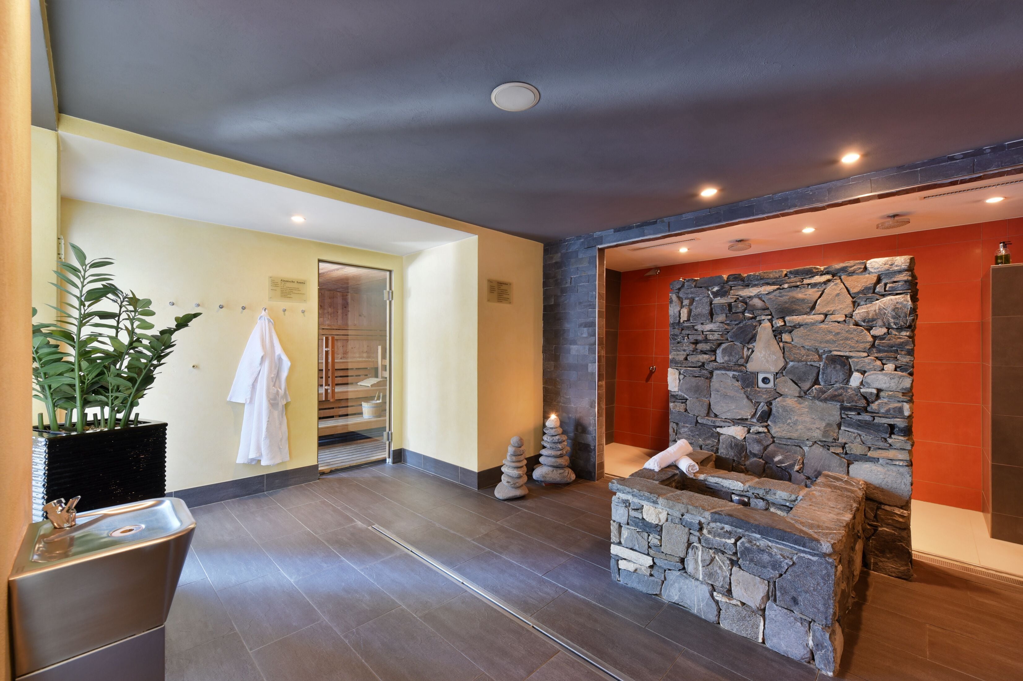 Un baño moderno con pared de piedra, un lavabo y un perchero para toallas.