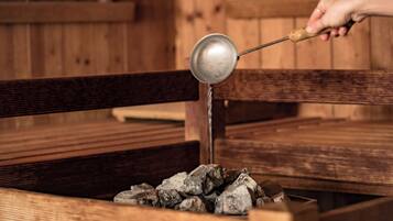 A wooden bench with a metal ladle pouring water over rocks.