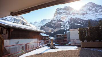 A snow-covered mountain landscape with a building and a red fence in the foreground.