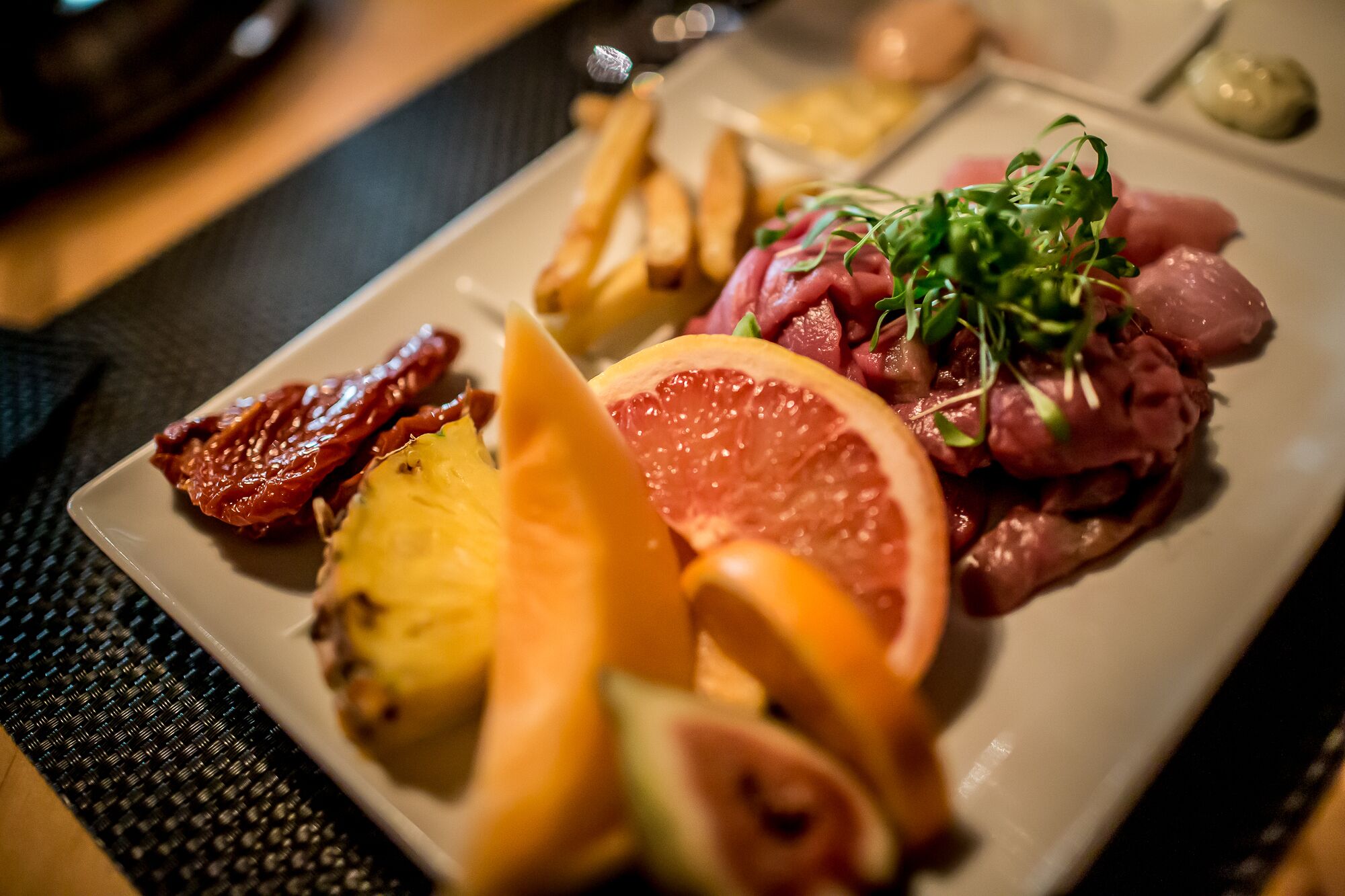 A plate with various food items including meat, potatoes, and citrus fruits.