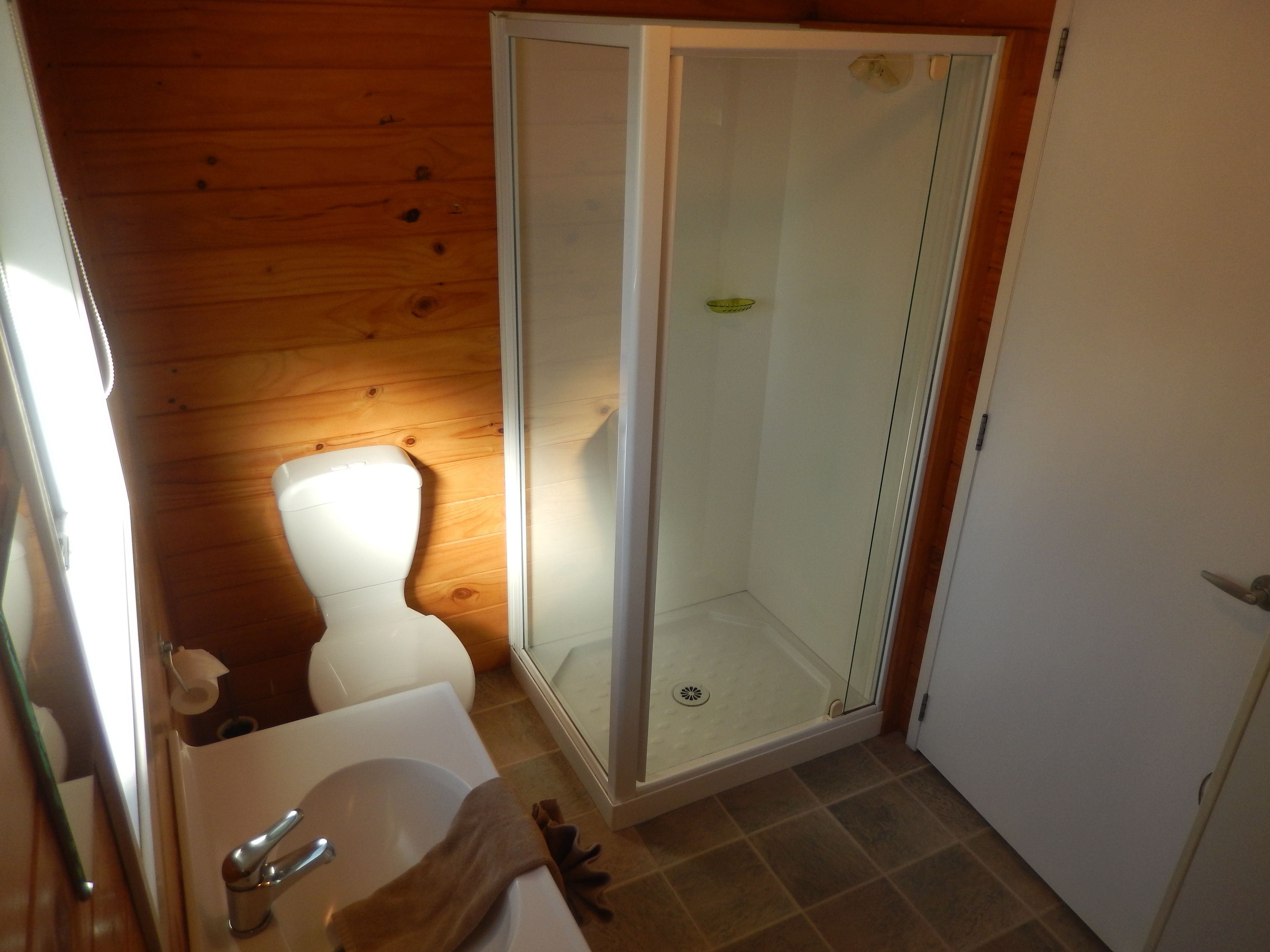 Een badkamer met toilet, wastafel en douche met glazen wanden.