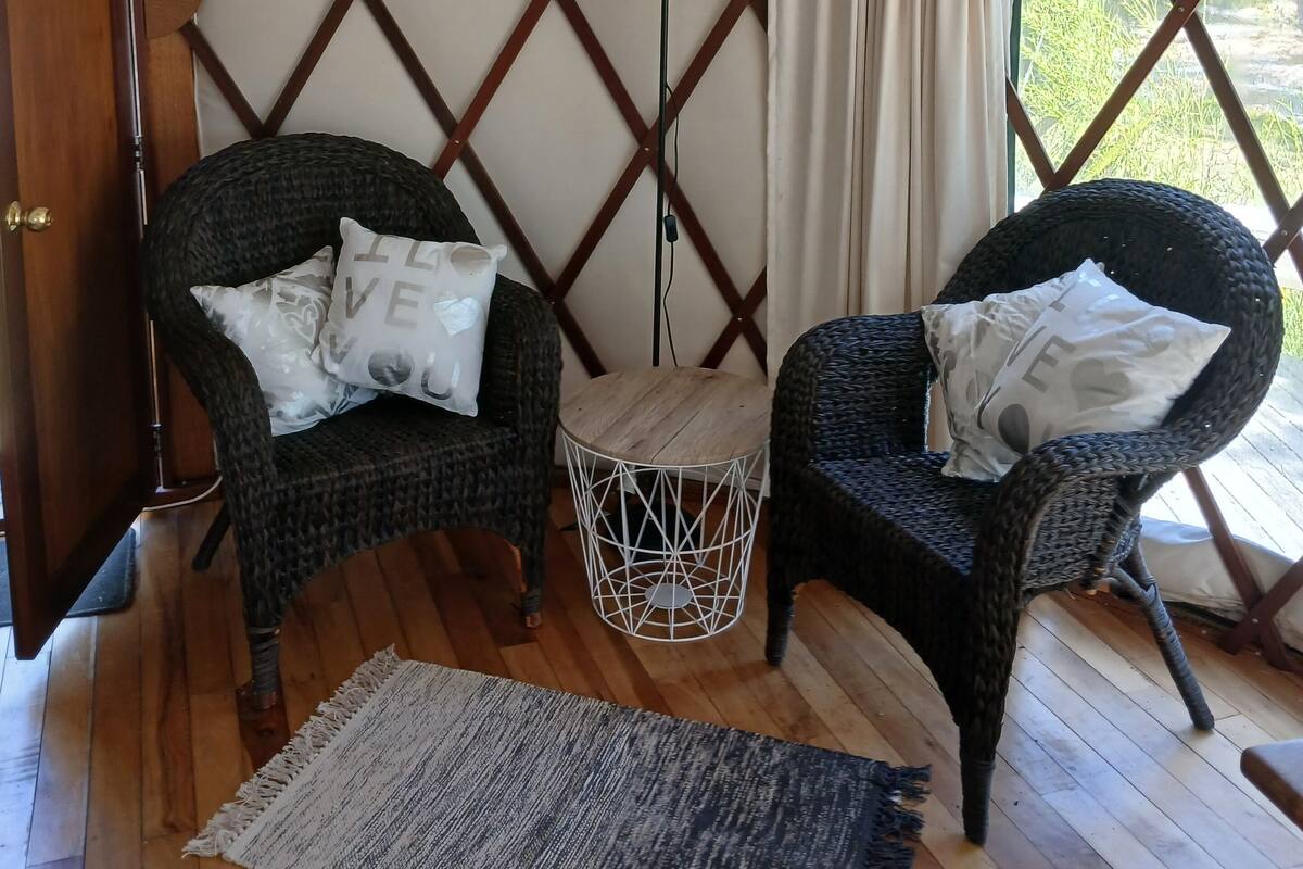 A cozy interior with two wicker chairs, a small round table, and a lamp.