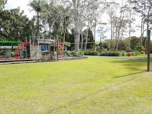 Explore the playground area surrounded by lush greenery and tall trees.