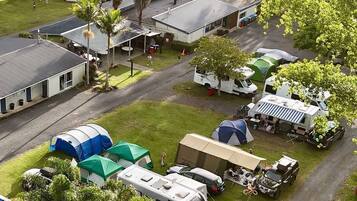 A campsite with RVs, tents, and a building with a flat roof.