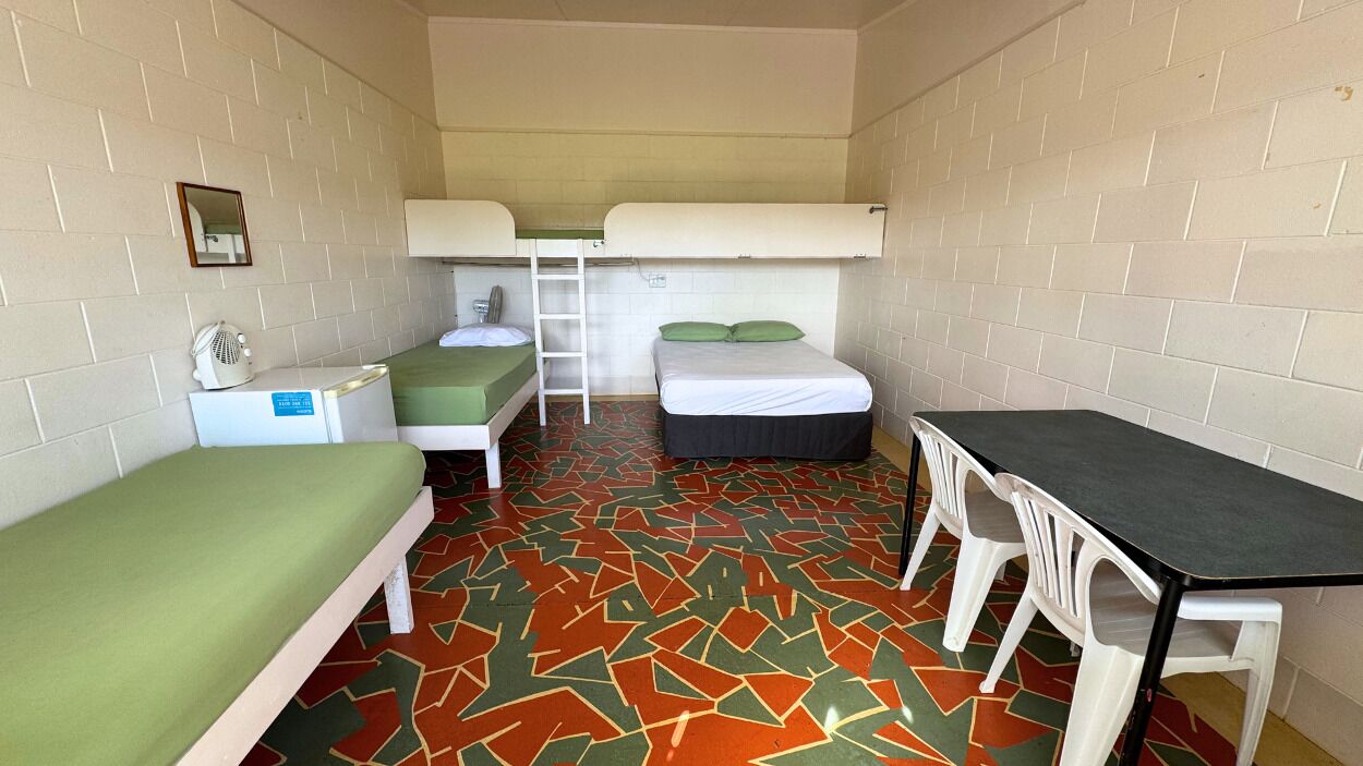 A compact room with bunk beds, a desk, and a chair.