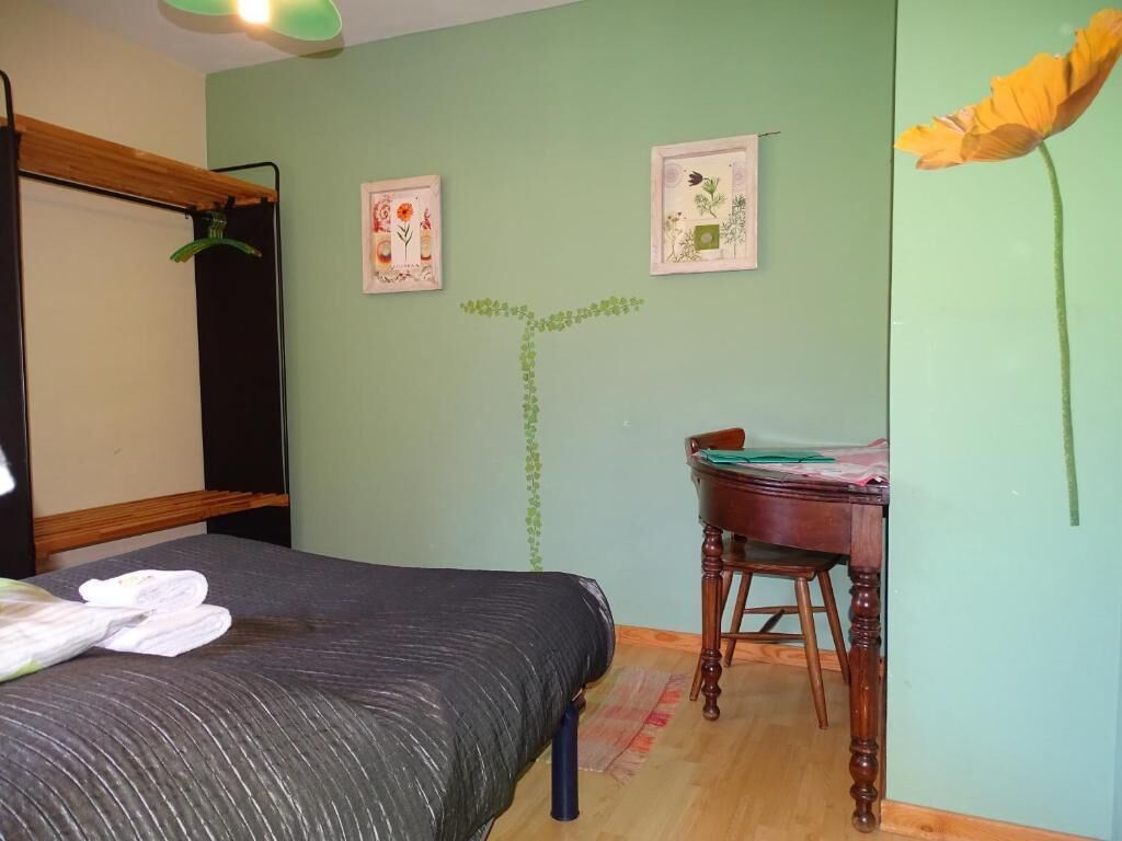 Une pièce comprenant un lit, une chaise en bois et deux tableaux encadrés accrochés au mur.