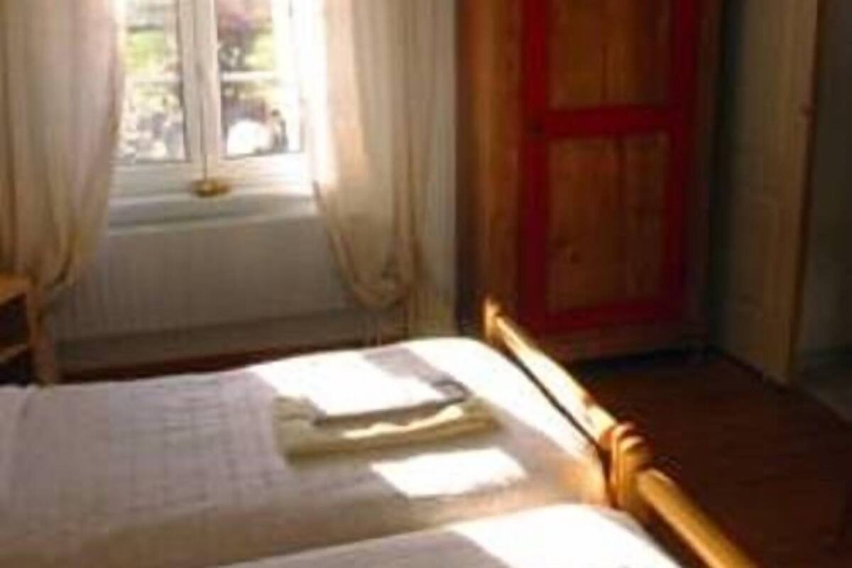 A room with a bed, a window with curtains, and a wooden door.