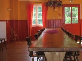 Un salón de conferencias con una larga mesa de madera, paredes rojas y una ventana con cortinas.